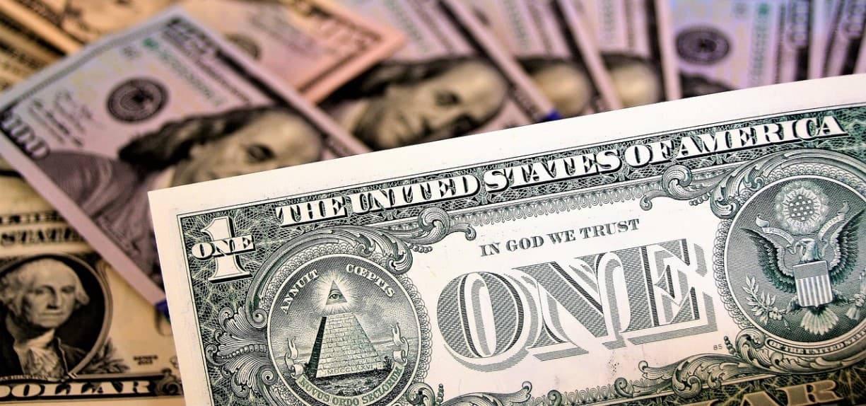 A single US dollar bill is held in the foreground, The image invites viewers to reflect on the Stocks Performance