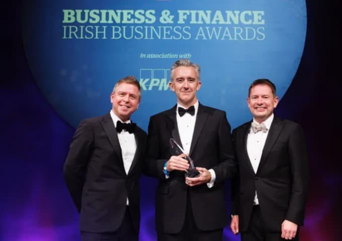 Ian Hyland, Fergal Leamy, and Séamus Hand stand together, each donning a black tuxedo and bow tie. Hyland and Hand smile broadly, while Leamy, CEO of Glen Dimplex, which was named Company of the Year 2023.